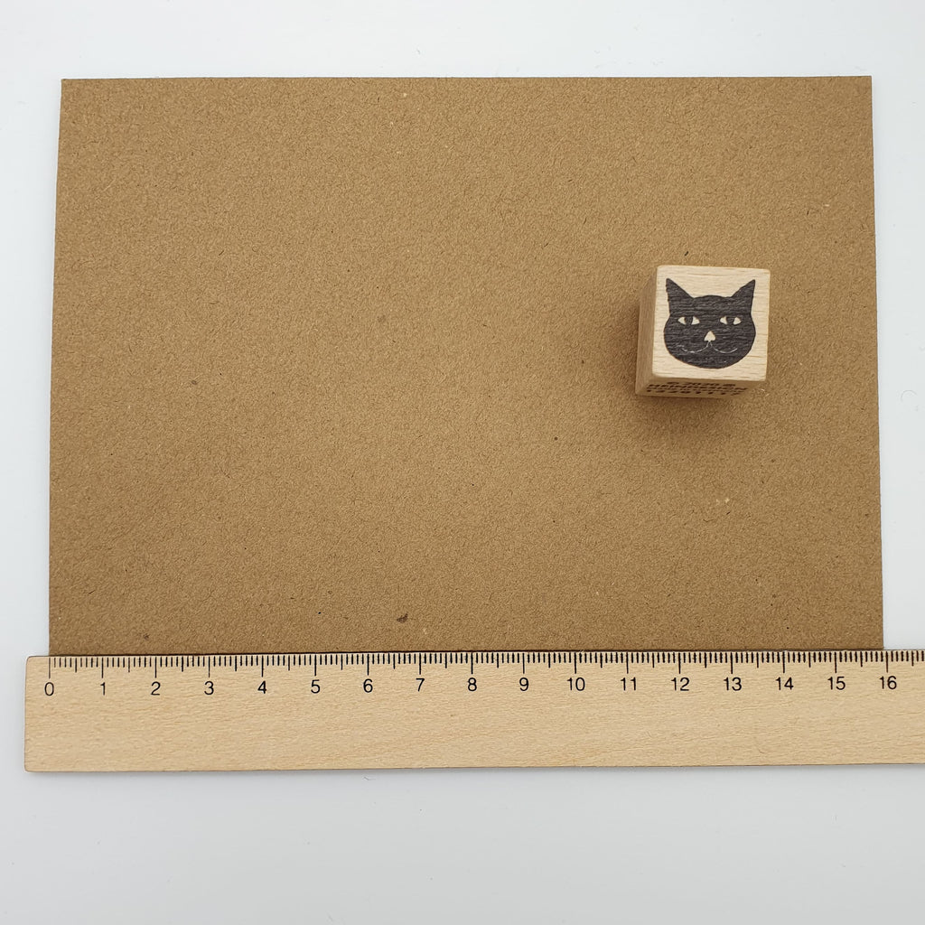 Stempel in Form eines Katzenkopfes auf einem braunen Briefumschlag mit Lineal