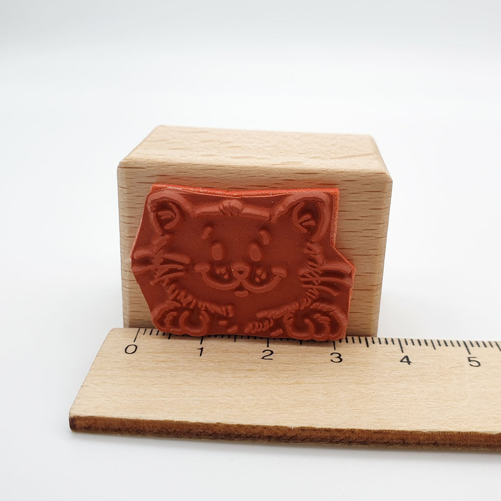 Stempel aus rotem Gummi mit dem Motiv einer lächelnden Katze mit Lineal