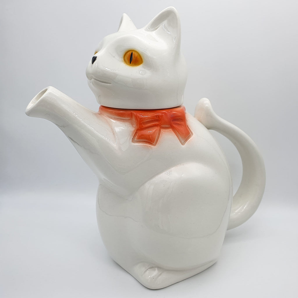 Weiße Kaffee- oder Teekanne in Form einer Katze mit einer roten Schleife