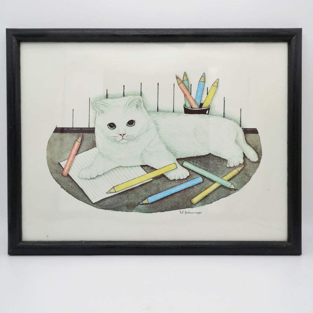 Bild einer weißen Katze mit Buntstiften in einem schwarzen Rahmen