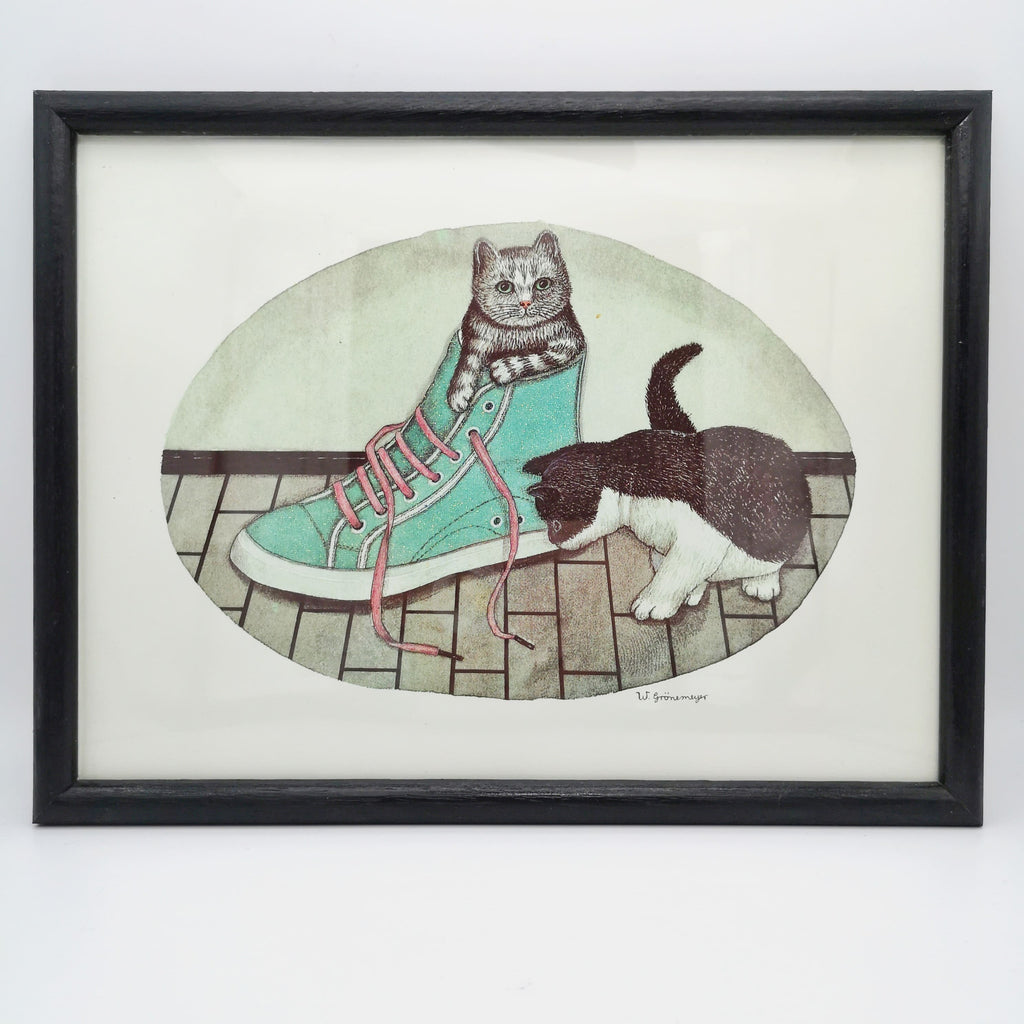 Bild zweier Katzen, die mit einem Schuh spielen in einem schwarzen Rahmen
