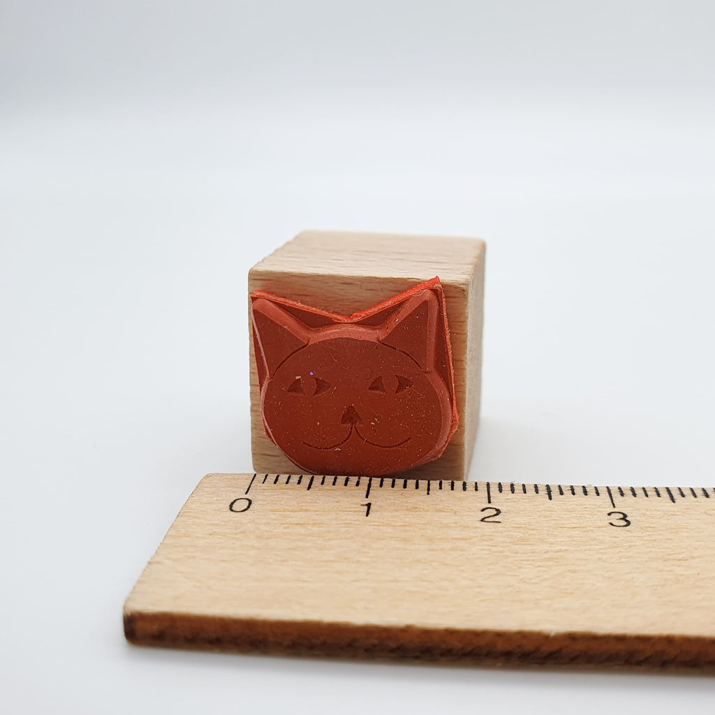 Stempel aus rotem Gummi in Form eines Katzenkopfes mit Lineal