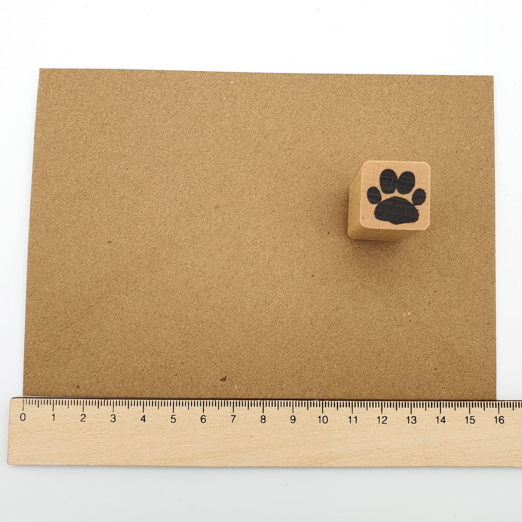 Stempel in Form einer Katzenpfote auf einem braunen Briefumschlag mit Lineal