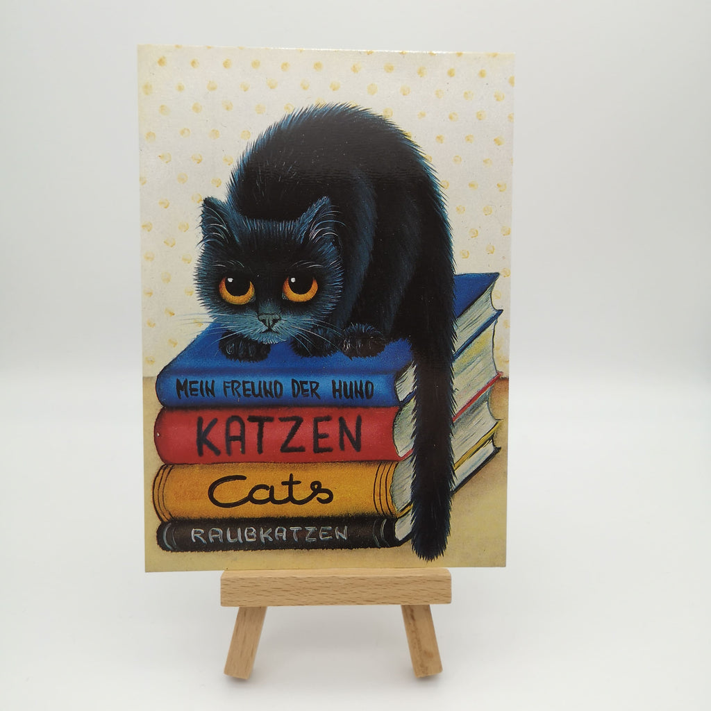 Postkarte mit einer schwarzen Katze auf einem Bücherstapel