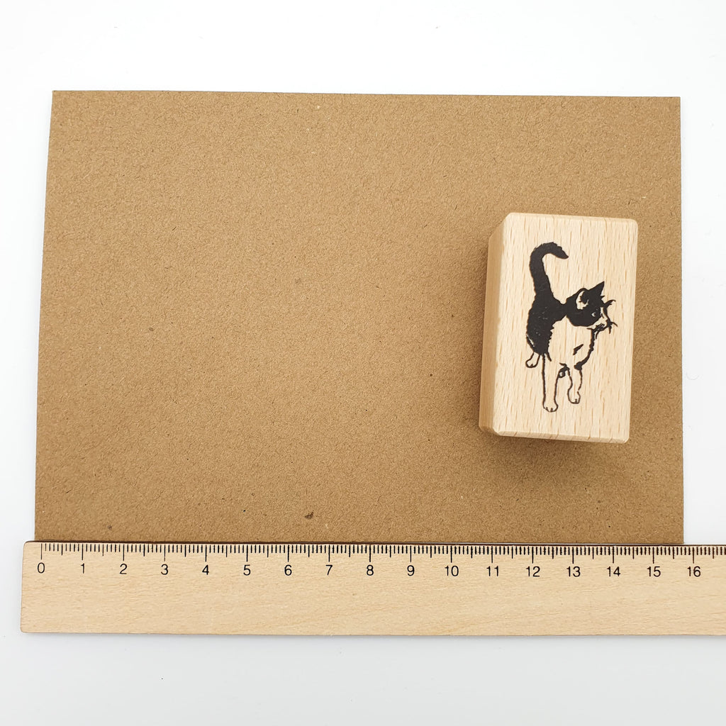 Stempel mit dem Motiv einer schwarz-weißen Katze auf einem braunen Briefumschlag mit Lineal