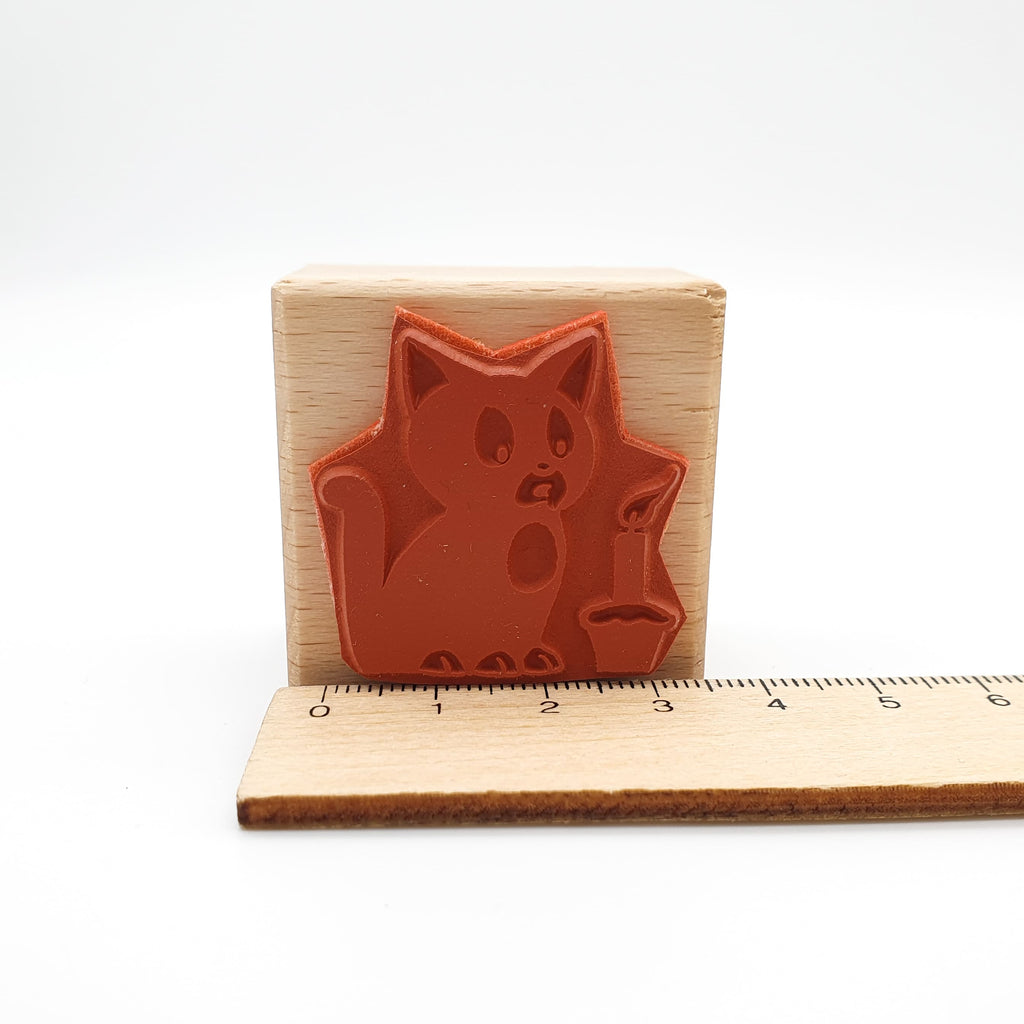 Stempel aus rotem Gummi mit dem Motiv einer Katze, die eine Kerze ausbläst