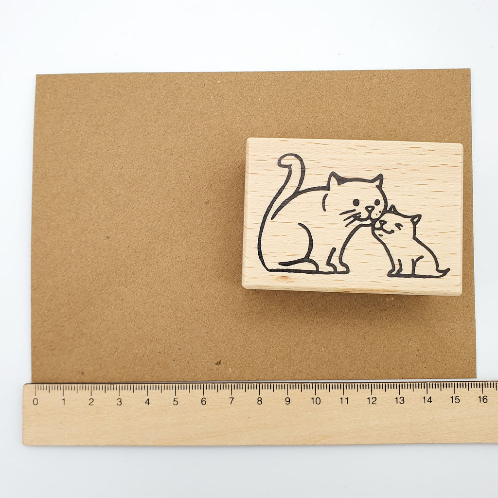 Stempel mit dem Motiv einer kleinen und einer großen Katze auf einem braunen Briefumschlag mit Lineal