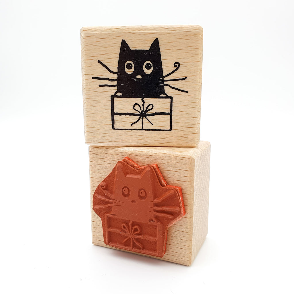 Stempel aus rotem Gummi mit dem Motiv einer Katze, die in einem Geschenk sitzt