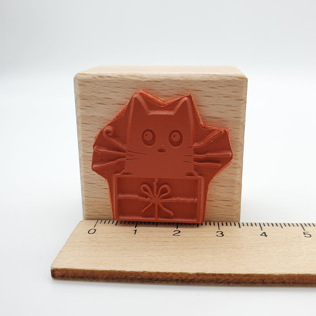Stempel aus rotem Gummi mit dem Motiv einer Katze, die in einem Geschenk sitzt