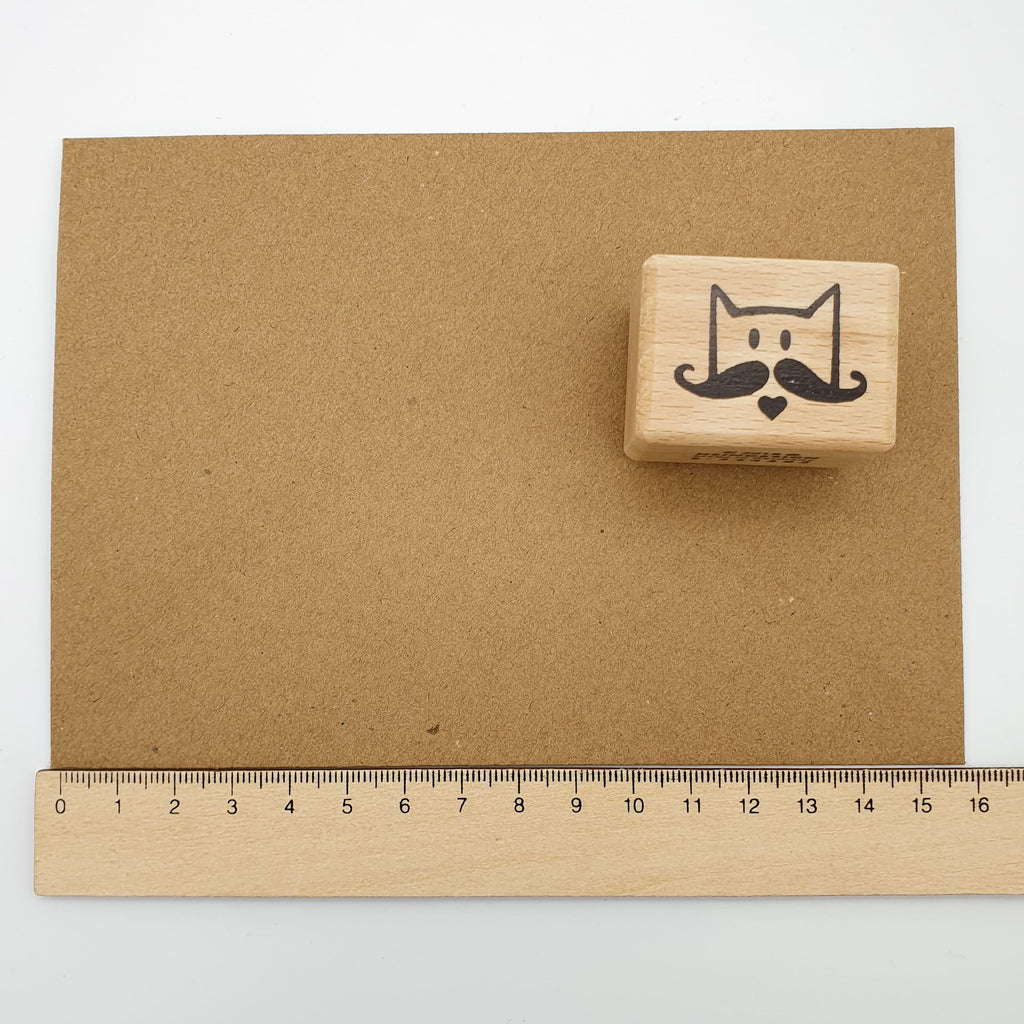 Stempel mit dem Motiv einer Schnurrbart-Katze auf einem braunen Briefumschlag mit Lineal