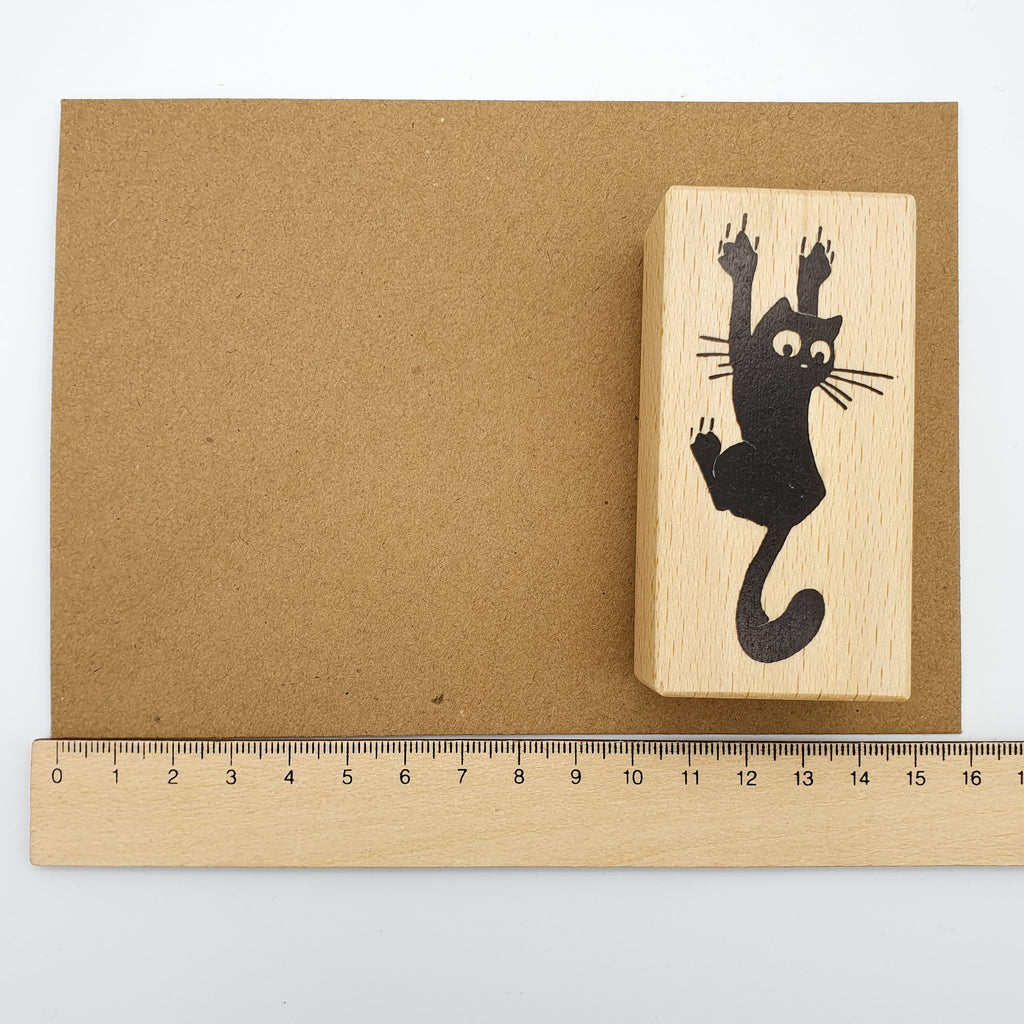 Stempel mit dem Motiv einer krallenden Katze auf einem braunen Briefumschlag mit Lineal