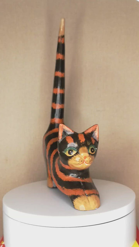 Katzenfigur aus Holz mit schwarz-orangenen Streifen in einer angriffslustigen Pose